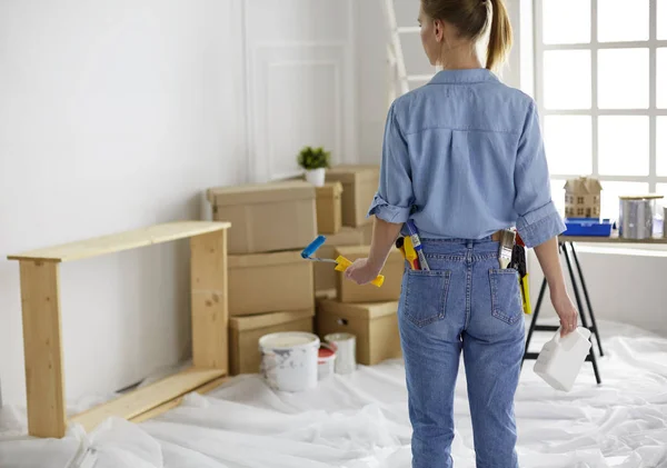 Pretty smilling woman painting interior wall of home with paint roller — 스톡 사진