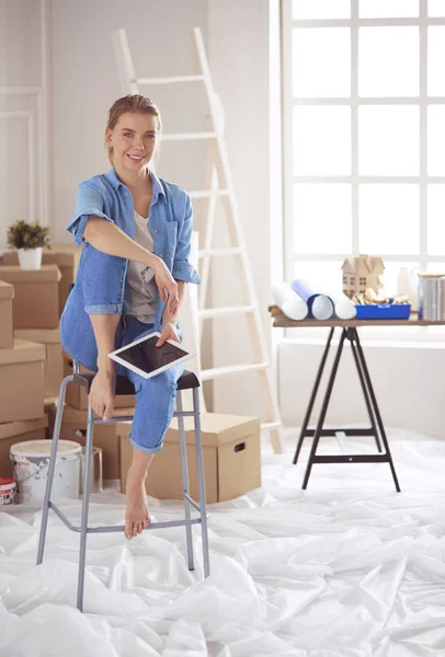 Jonge vrouw zit op een witte stoel in een lege kamer, denkend aan iets — Stockfoto