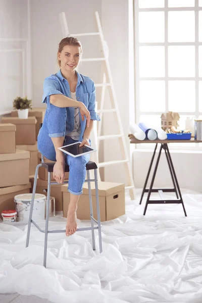 Giovane donna seduta su una sedia bianca in una stanza vuota, pensando a qualcosa — Foto Stock