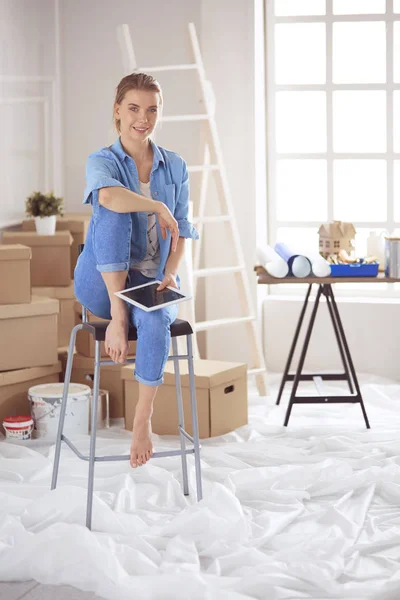 Mujer joven sentada en una silla blanca en una habitación vacía, pensando en algo — Foto de Stock