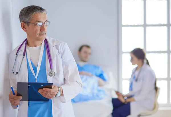 Médico segurando pasta na frente de um paciente e um médico — Fotografia de Stock