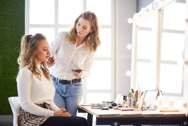 Makyaj sanatçısı genç ve güzel gelinin makyajını yapıyor.