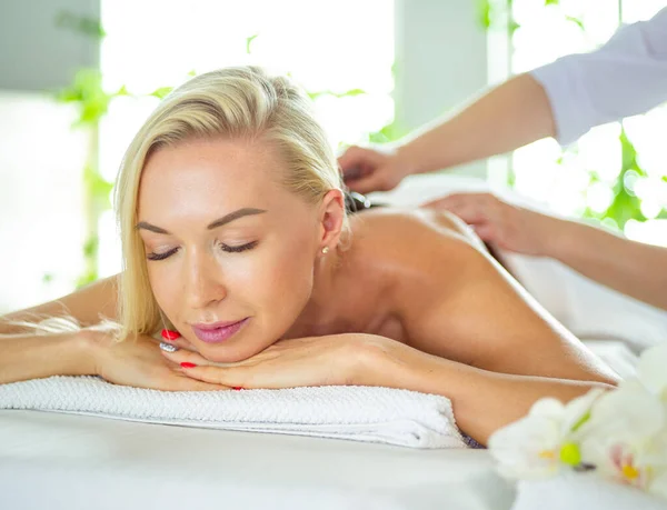 Jovem mulher no salão de spa, recebendo pedras massagem — Fotografia de Stock