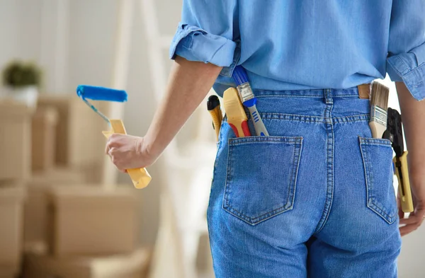 Mujer bonita pintando la pared interior del hogar con rodillo de pintura — Foto de Stock