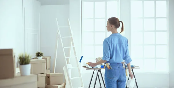 Glad kvinna målar väggen med roller i hemmet — Stockfoto