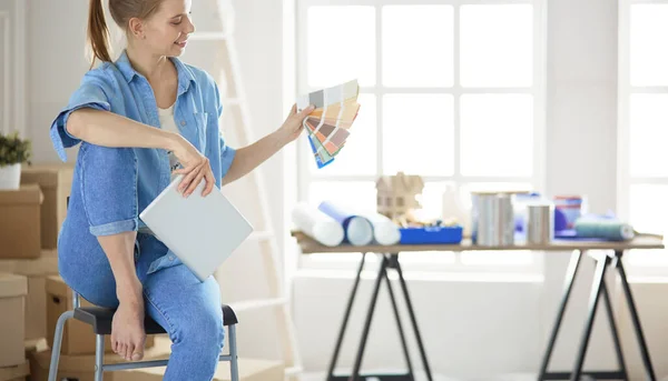 Joven hermosa mujer sosteniendo paleta de colores, de pie cerca de la pared — Foto de Stock