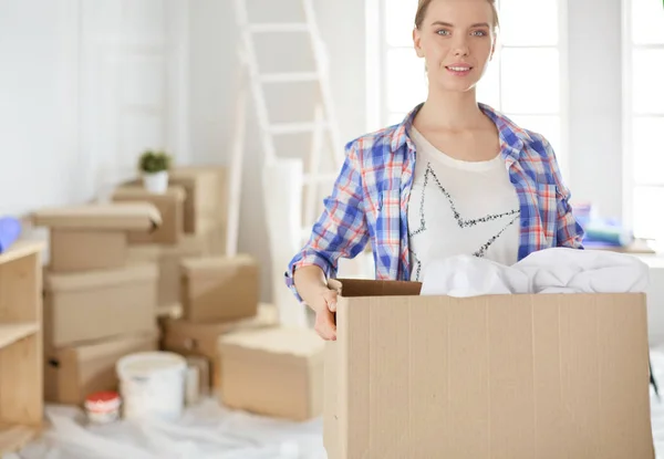 Egy gyönyörű, egyedülálló fiatal nő dobozokat pakol ki és új otthonba költözik. — Stock Fotó