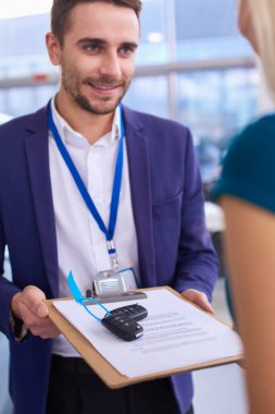 Araba satıcısı araba galerisindeki mutlu müşteriye araba satar ve anahtarları teslim eder.