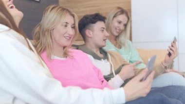 Güzel genç insanlar akıllı telefonlar kullanarak ve yerde otururken gülümseyen