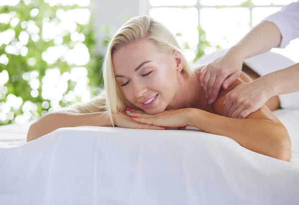 Menina jovem e bonita relaxante no salão de spa. Terapia de massagem durante o verão sazonal ou fundo de primavera — Fotografia de Stock