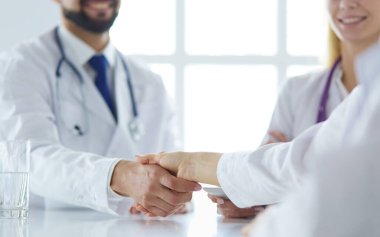 Doktor ofiste erkek bir hastayla el sıkışıyor.