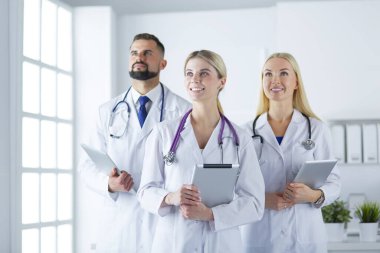 Gülümseyen doktorlar çalışırken bir arada duruyorlar.