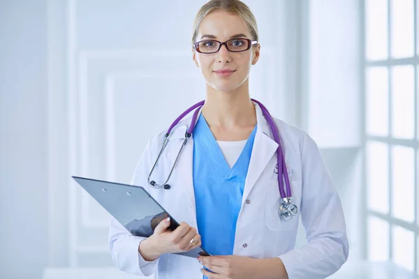 Médecin souriante avec un dossier en uniforme debout — Photo