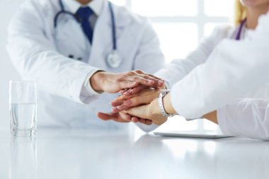 Doktorlar el ele tutuşup yakın çekim yapıyor.