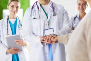 Doktorlar ve hemşireler tıbbi bir ekipte el ele tutuşuyorlar.