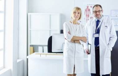 Ciddi bir tıbbi ekip parlak bir ofiste dizüstü bilgisayar kullanıyor.