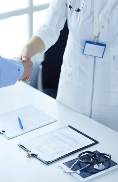 Female doctor handshaking a patients hand and smiling