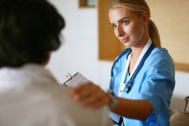 Kadın doktor yaşlılara hastanede el ele tutuşmalarında yardım ediyor