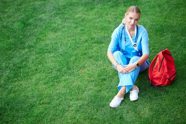 Porträtt av kvinnlig läkare sitter på gräs — Stockfoto