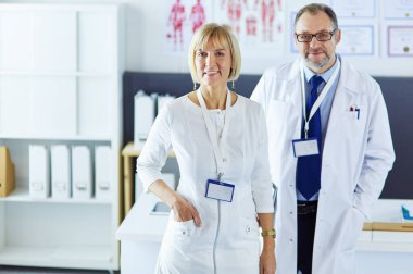 Ciddi bir tıbbi ekip parlak bir ofiste dizüstü bilgisayar kullanıyor.