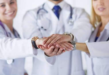 Doktorlar ve hemşireler tıbbi bir ekipte el ele tutuşuyorlar.