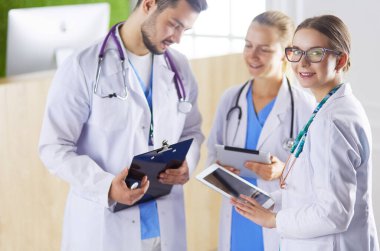 Doktorlar hastanede tablet kullanıyorlar. Ofiste duruyorlar.