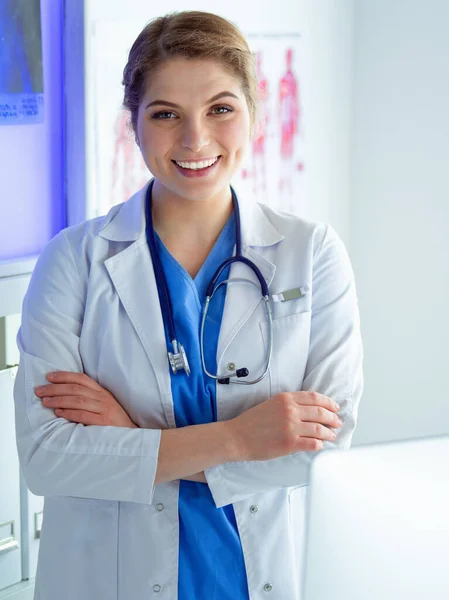 Mujer joven médica en uniforme blanco de pie en la oficina de clínicas — Foto de Stock