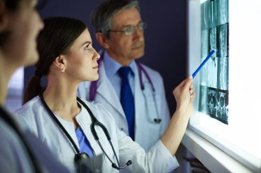Bir grup doktor bir klinikte röntgenleri inceliyor, teşhis koymayı düşünüyorlar.