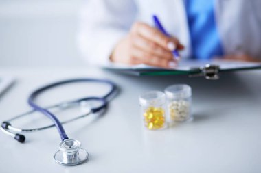 Elinde bir kutu beyaz hap ve masada yazılı tedavi planı tutan bir kadın.