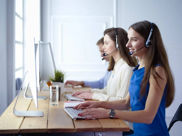 Πορτρέτο του νεαρού χειριστή τηλεφωνικού κέντρου φορώντας ακουστικά με συναδέλφους που εργάζονται στο παρασκήνιο στο γραφείο — Φωτογραφία Αρχείου
