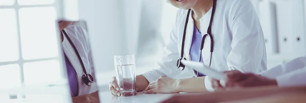 Médico sonriente usando un portátil trabajando con sus colegas en una habitación de hospital luminosa —  Fotos de Stock