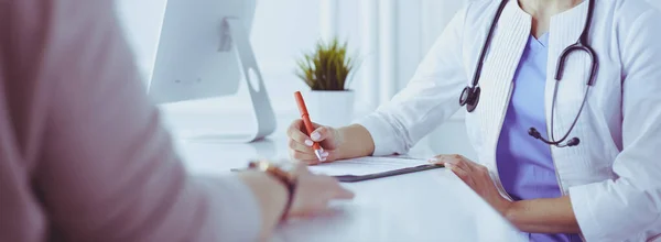 Doctor and patient discussing medical problems in a hospital consulting room. Doc filling in a patients form — Stock Photo, Image