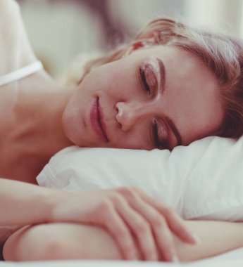 Güzel bir kadın yatağında uzanıyor..