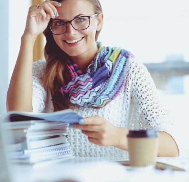 Kitapların arasında masa başında oturan genç bir kadın.