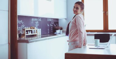 Cep telefonu ayakta modern mutfak kullanan kadın