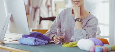 Moda tasarımcıları stüdyoda çalışıyor. Masanın üzerinde oturuyorlar.