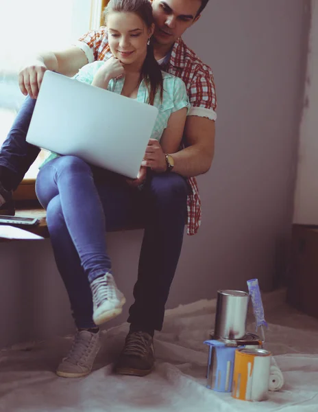 Retrato de jovem casal em movimento em nova casa sentado com laptop — Fotografia de Stock