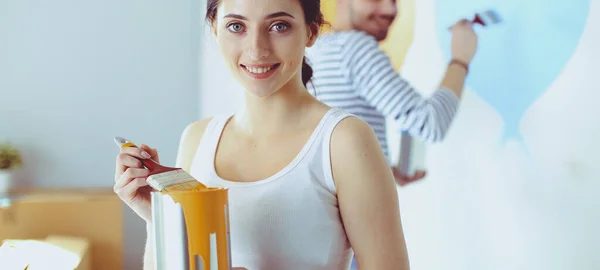 Portrait de heureux sourire jeune couple peinture mur intérieur de la maison neuve — Photo