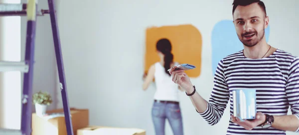 Portrait of happy smiling young couple painting interior wall of new house. young couple — Stock Photo, Image