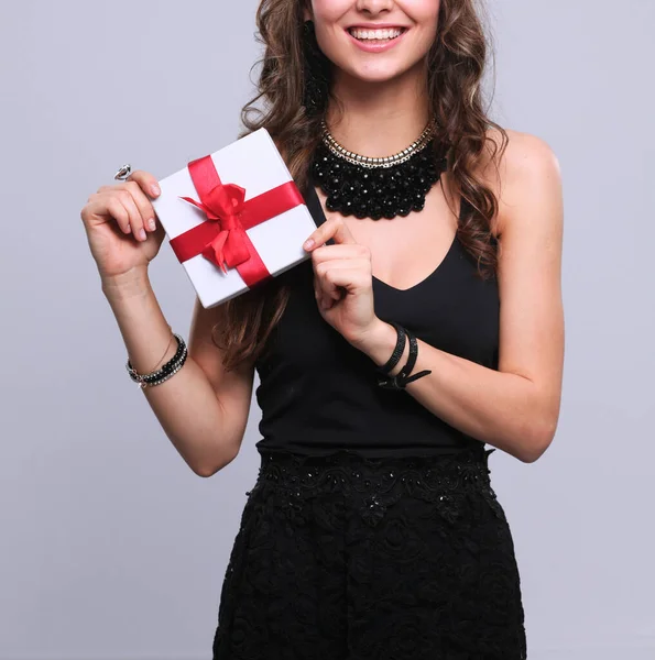 Young woman holding a gift box isolated on gtay background — Stock Photo, Image