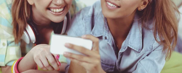 Two girls taking pictures on the phone at home — Stock Photo, Image