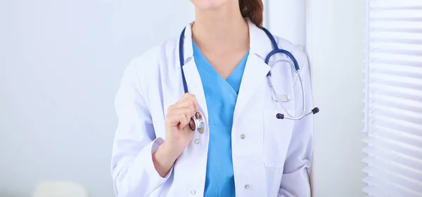 Kobieta lekarz stoi w pobliżu okna z skrzyżowanymi ramionami, odizolowany — Zdjęcie stockowe