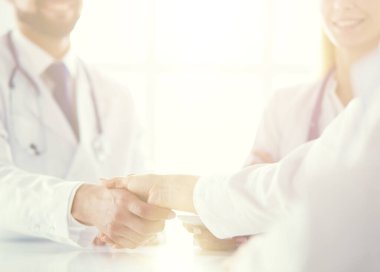 Doktor ofiste erkek bir hastayla el sıkışıyor.