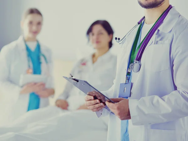 Beau médecin parle avec une jeune patiente et prend des notes alors qu'il est assis dans son bureau — Photo