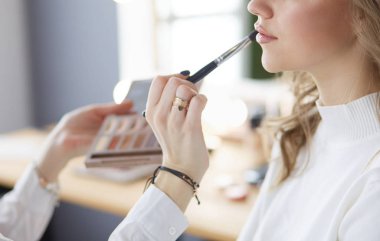 Güzel, genç bir model kadın makyaj yaptırıyor.