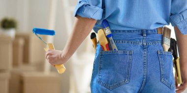 Güzel bir kadın evin iç duvarını boya ile boyuyor.