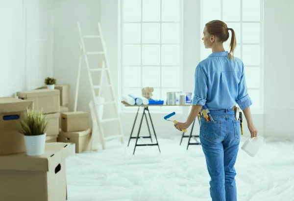 Mooie glimlachende vrouw schilderen interieur muur van huis met verfroller — Stockfoto