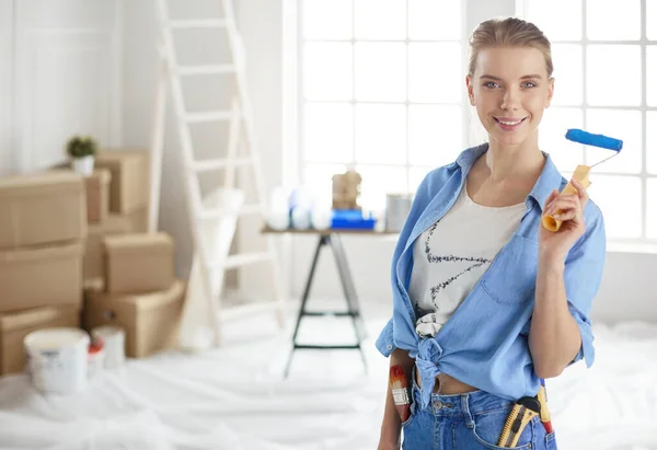 Pretty smilling woman painting interior wall of home with paint roller — 스톡 사진