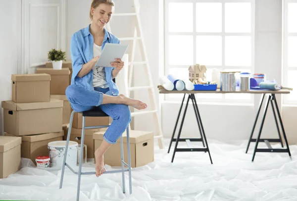 Jonge vrouw zit thuis en koopt nieuwe meubels via internet met behulp van een tablet computer — Stockfoto