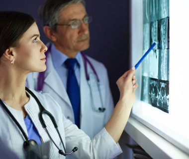 Bir grup doktor bir klinikte röntgenleri inceliyor, teşhis koymayı düşünüyorlar.